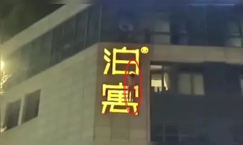 Homem pendurado em letreiro tenta escapar de flagra na China